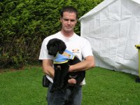 Foto: Der Führhundtrainer Pierre Henry hält den schwarzen Welpen im Arm