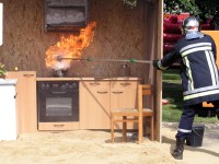 Foto: Ein Feuerwehrmann demonstriert die Stichflamme, die entsteht, wenn ein Topf mit brennendem Fett mit Wasser gelscht wird.