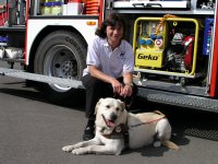 Photo: Josiane Rommes et chien guide Urak devant un camion de pompiers.