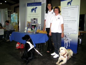 Foto: Martine Konsbruck und Josiane Rommes mit Fhrhund Urak neben dem Stand.