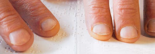 Bildbeschreibung: Finger lesen Braille auf einem Papier